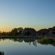 Humusland Hofteich mit Spiegelung der Gebäude in der Abenddämmerung